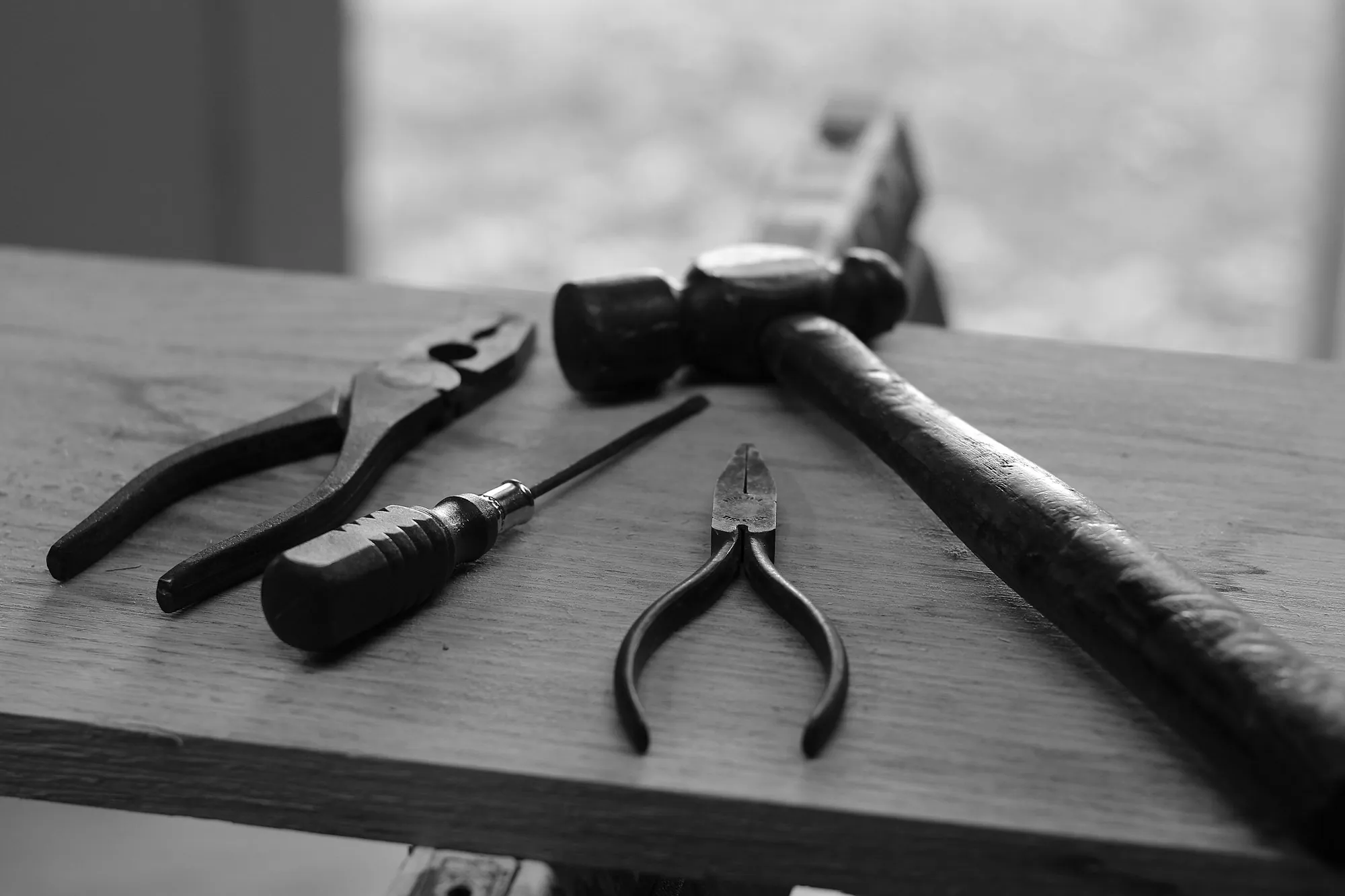 Hammer, pliers and screwdriver on a dark wooden bench